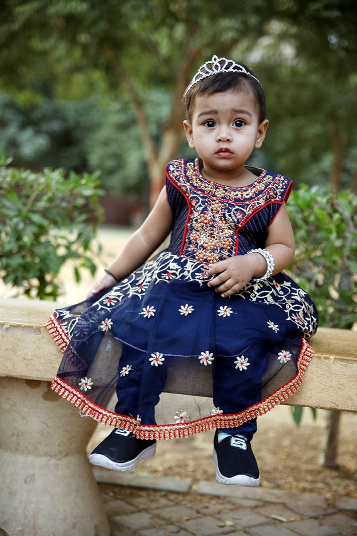 Child in a navy embroidered party frock made by Faraak, Karachi