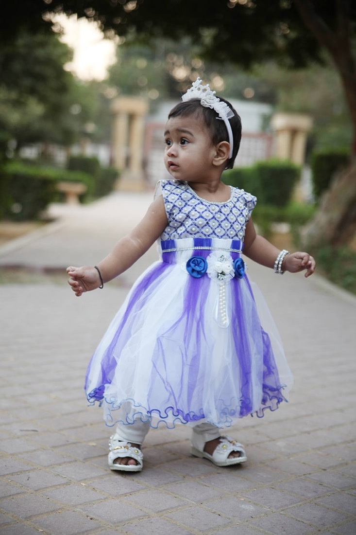 Child in a purple and white tulle party frock stitched at Faraak